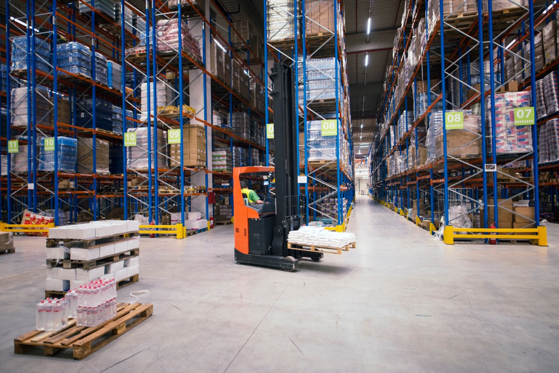 Forklift ve paletli raflarla dolu lojistik deposu
