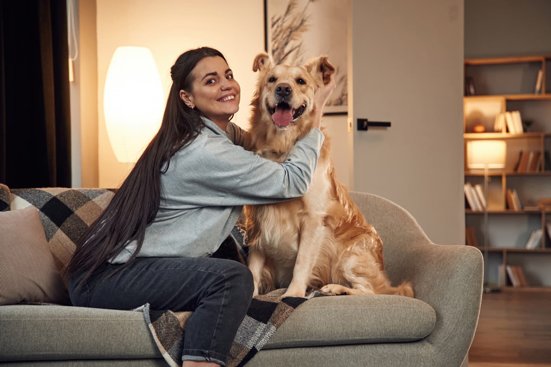 Evde kanepede golden retriever köpeğiyle oynayan kadın